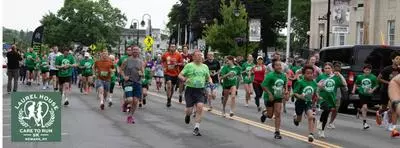 Picture of runners in green shirts running down a roadway